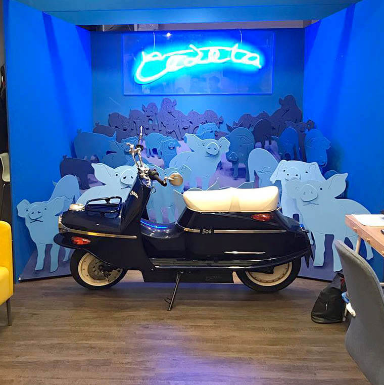 Čezeta Type 506 en un stand decorado con cerdos